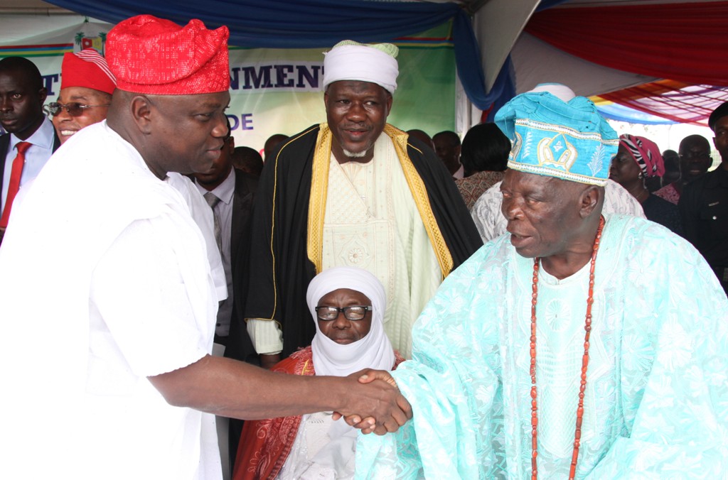 Lagos State Governor, Mr. Akinwunmi Ambode (left), in a warm handshake with the Alara of IIlara-Epe, Oba Hakeem Adesanya (right) while the Chief Imam of Lagos, Alhaji Garba Ibrahim Akinola (sitting) watches during the commissioning of 20 Mobile Care Unit and 26 Number Transport Ambulances at Lagos House, Ikeja, on Monday, August 31, 2015.